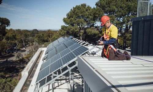 a man in a hard hat on a roof with solar panels